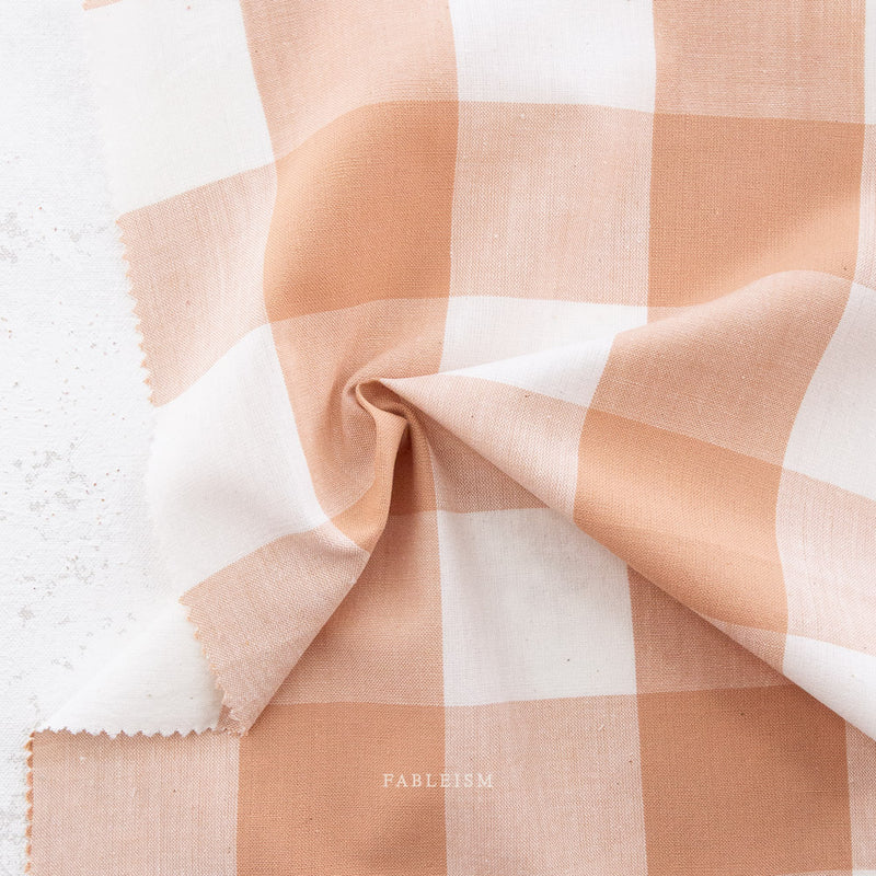 Checkered fabric swatch with pink  and white pattern on a textured surface, 