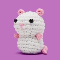 White crochet rat with pink ears and feet on a purple background