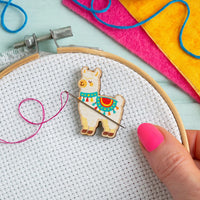 Embroidery hoop with an alpaca needle minder and colorful threads on a light blue background