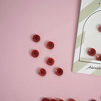 6 red buttons on a pink background