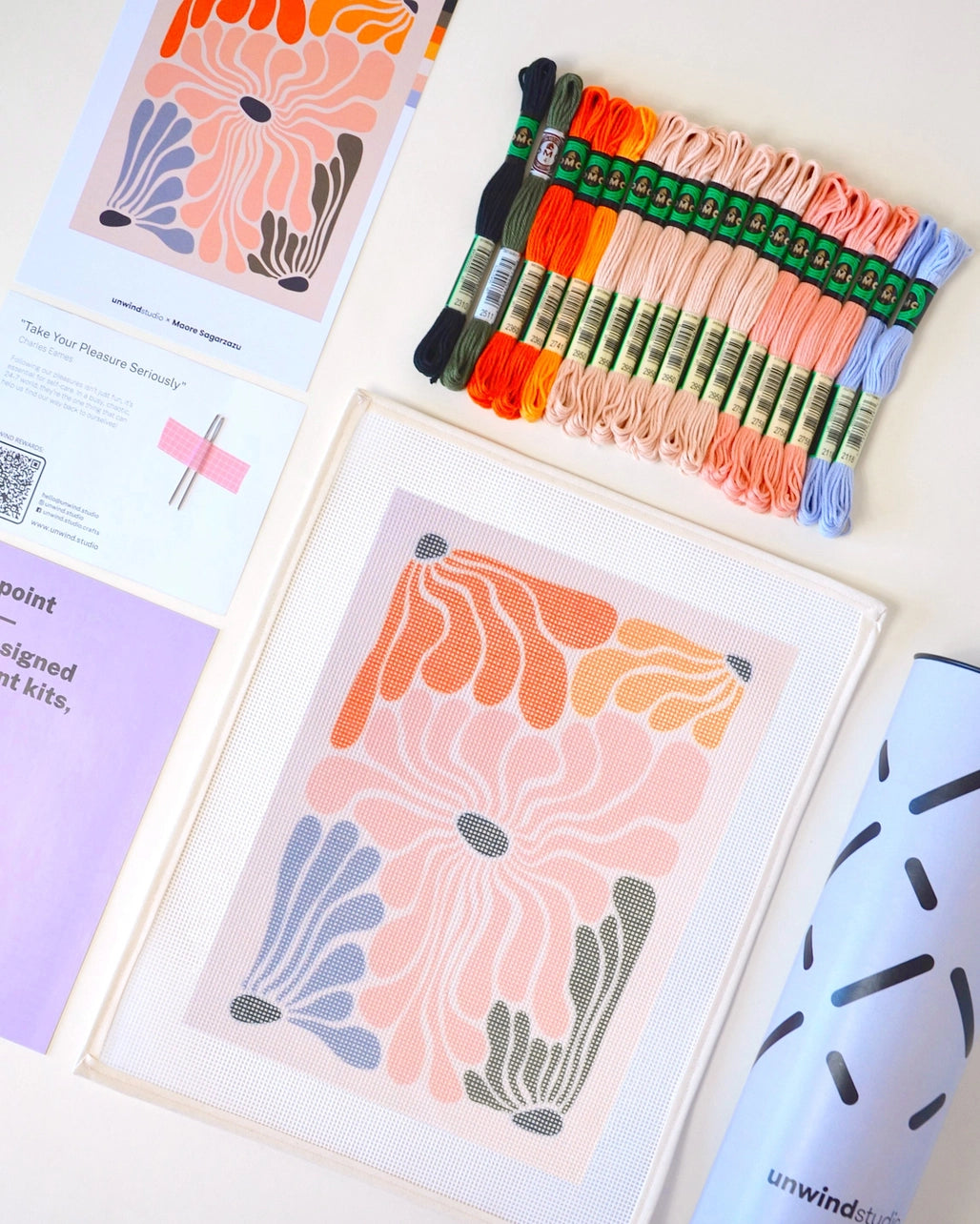 Needlepoint kit materials including canvas, thread, and instructions on a white background