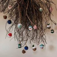 Many colorful christmas baubles hang from branches, pictured are snowman, night sky, and candy cane themed baubles. 