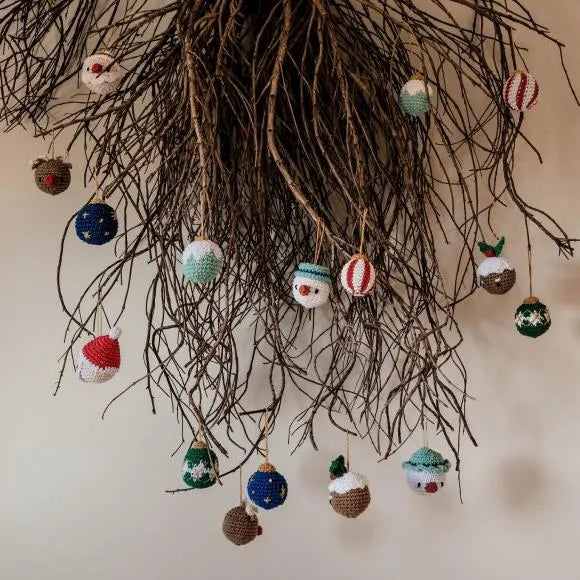 Many colorful christmas baubles hang from branches, pictured are snowman, night sky, and candy cane themed baubles. 