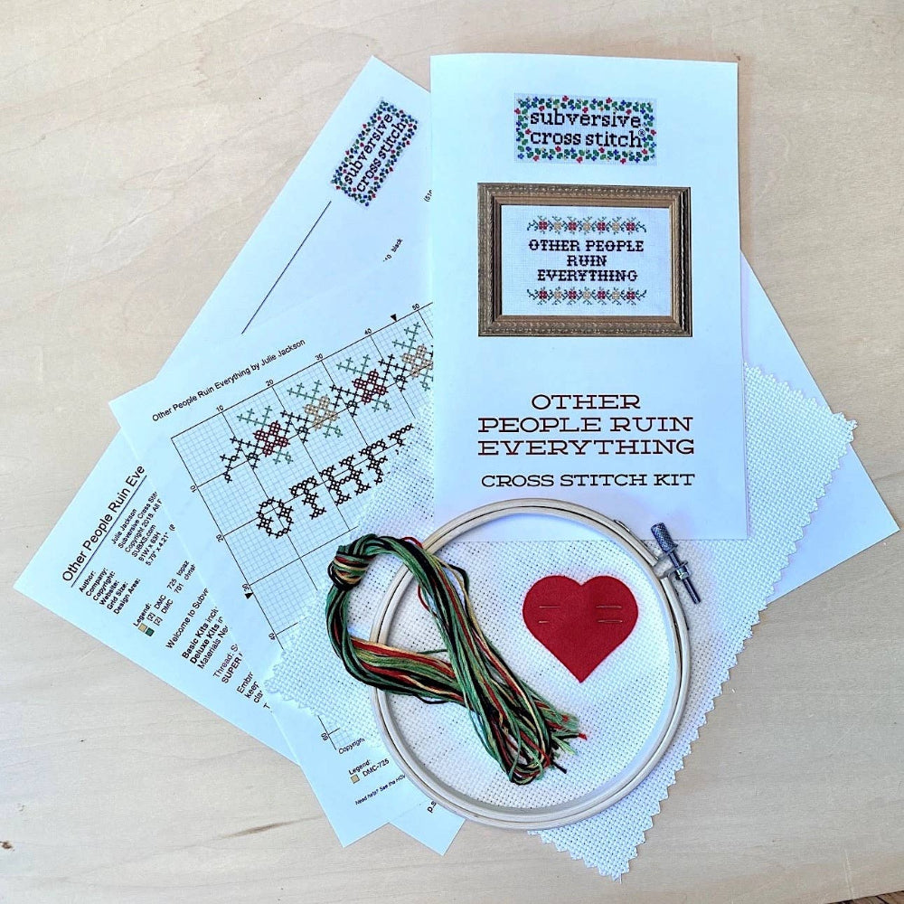 Cross stitch kit with pattern, floss, and hoop on a wooden surface