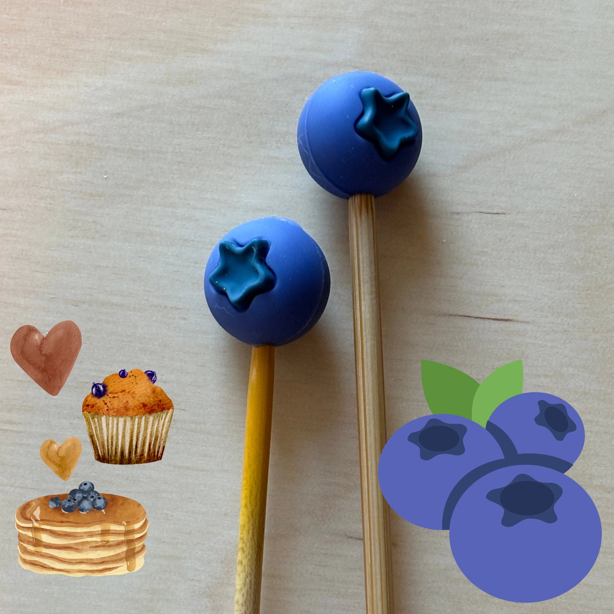 Two blueberry silicone ends on needles with illustrations of a muffin and pancakes on a light wood background.