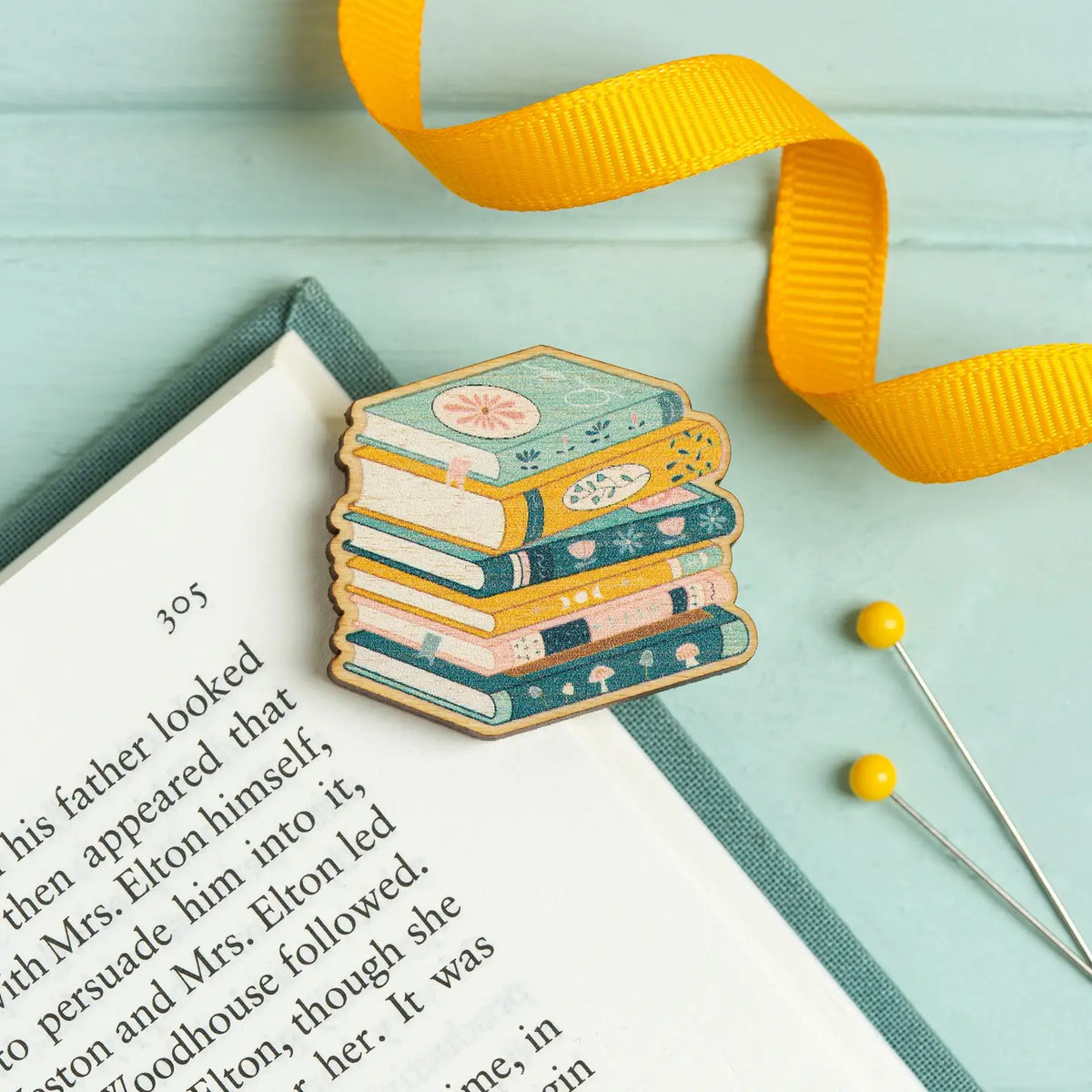 Stack of books needle minder with yellow ribbon on an open book