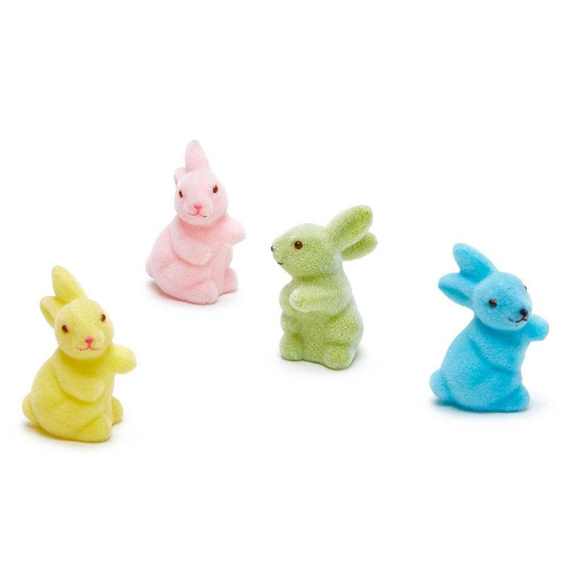 Flocked bunny figurines in pastel colors yellow, pink, green and blue, standing in a row.