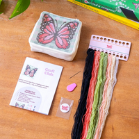 The kit for the needlepoint pouch showing all the included materials like colorful yarn, a needle, pre-sewn pouch and instructions