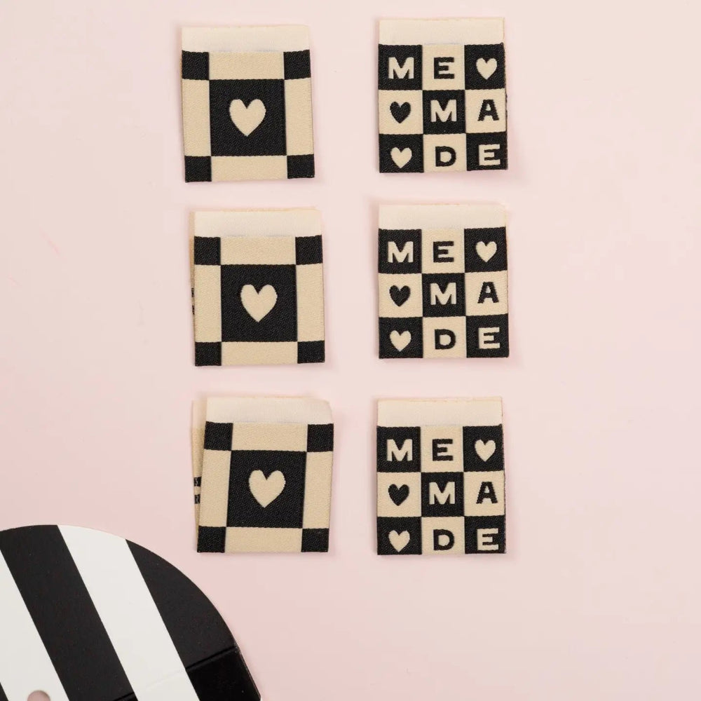 Set of decorative labels with checkered patterns and 'ME MADE' text on a pink background