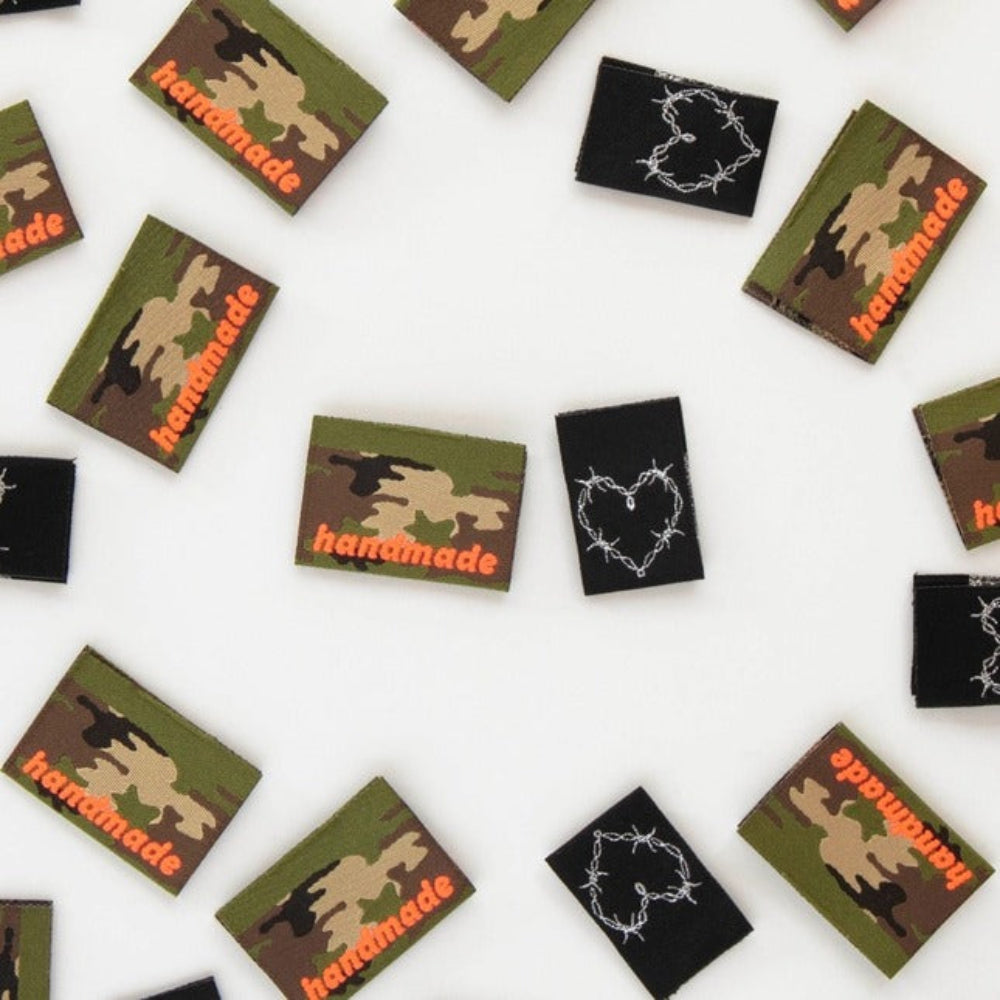 Collection of small rectangular patches with 'handmade' text and barbed wire heart on a white background.