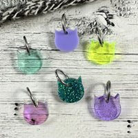 Colorful cat-shaped stitch markers on a wooden surface