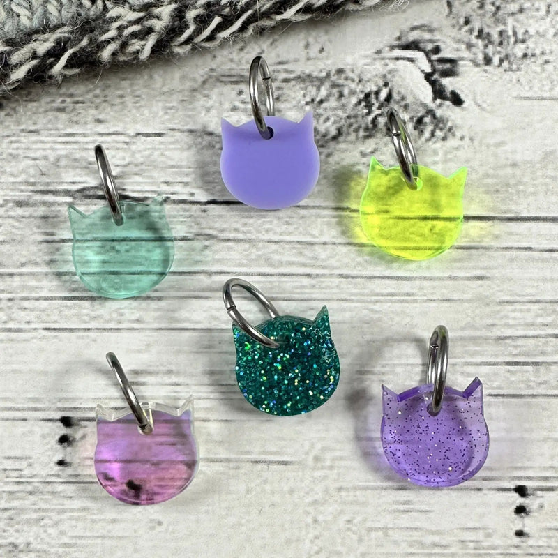 Colorful cat-shaped stitch markers on a wooden surface