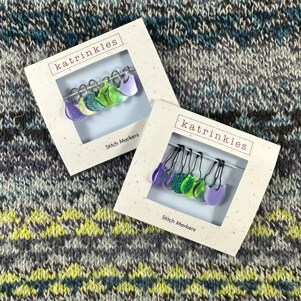 Two boxes of katrinkles stitch markers on a knitted fabric background