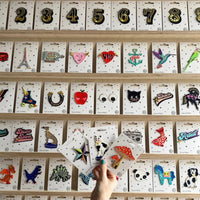Collection of various patches on display with a hand holding three patches.