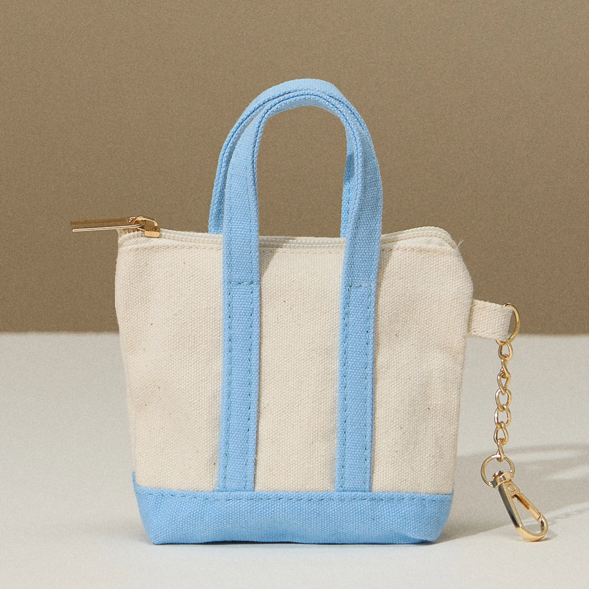Small tote bag with blue handles and trim on a beige background