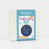 Embroidery kit packaging with a blue and white design on a white background