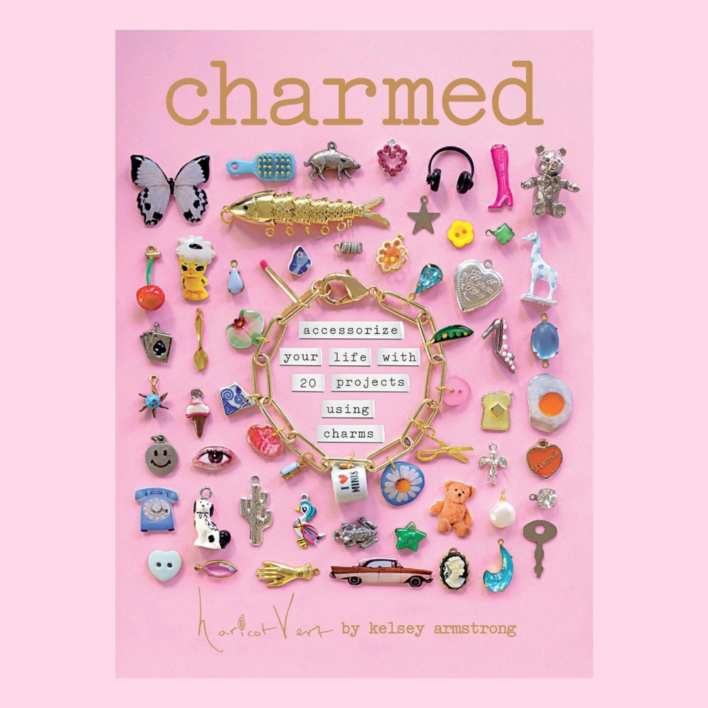 The book "Charmed" by Kelsey Armstrong with a cover featuring many cute charms against a pink background