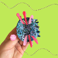 Hand holding a colorful yarn ball with pink crochet and knitting tools against a green background
