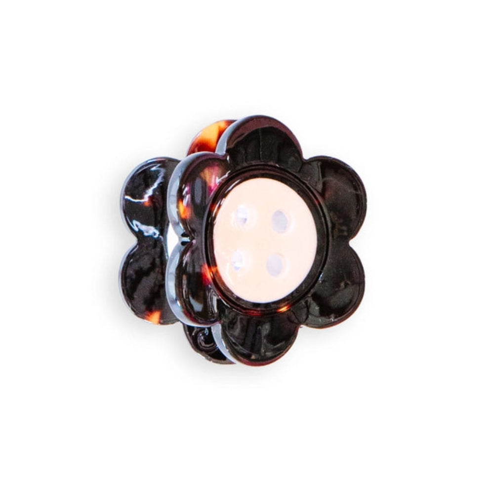 A mini daisy shaped claw clip with tortoise petals and a white button center is against a white background. 