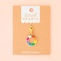 A zipper charm featuring a color wheel on Sarah Hearts packaging against a pink background.