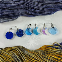 Set of colorful yarn markers with blue and golden yellow yarn in the background