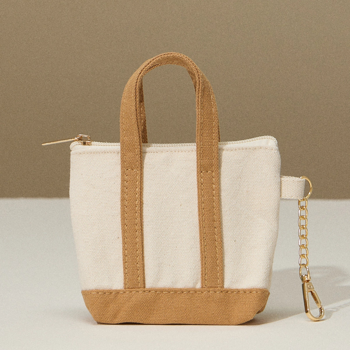 Small tote bag with brown handle and base on a beige background