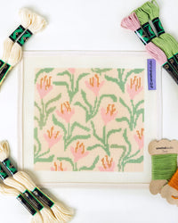 Cross-stitch kit with floral pattern and embroidery threads on a white background