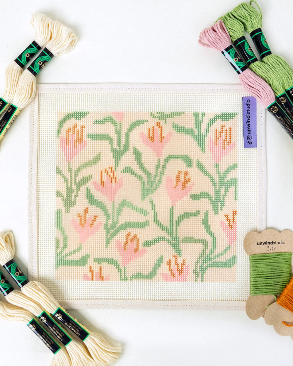 Cross-stitch kit with floral pattern and embroidery threads on a white background