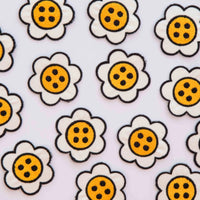 Daisy button shaped patches, scattered on a white background. 