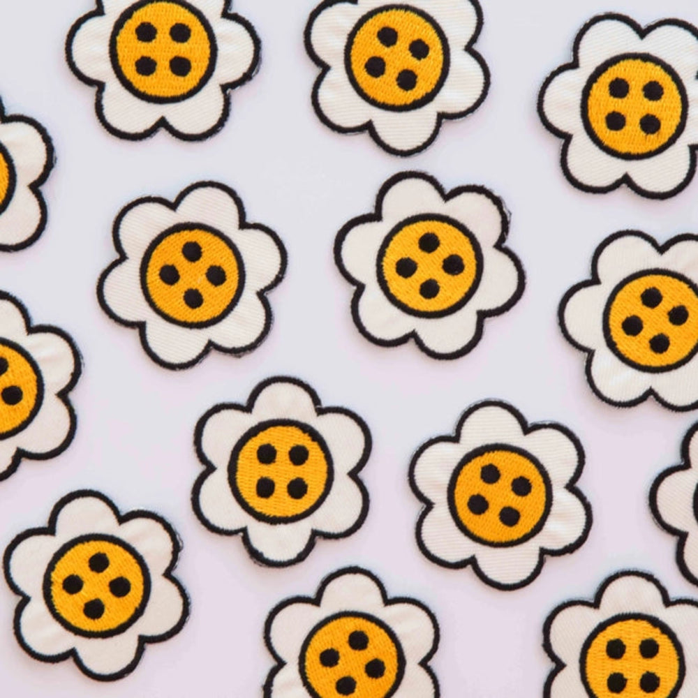 Daisy button shaped patches, scattered on a white background. 