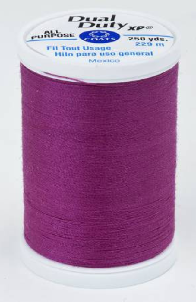 A spool of fuchsia Dual Duty XP sewing thread with a white label featuring blue and black text, set against a plain white background.