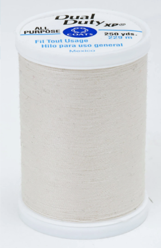 A spool of cream Dual Duty XP sewing thread with a white label featuring blue and black text, set against a plain white background.