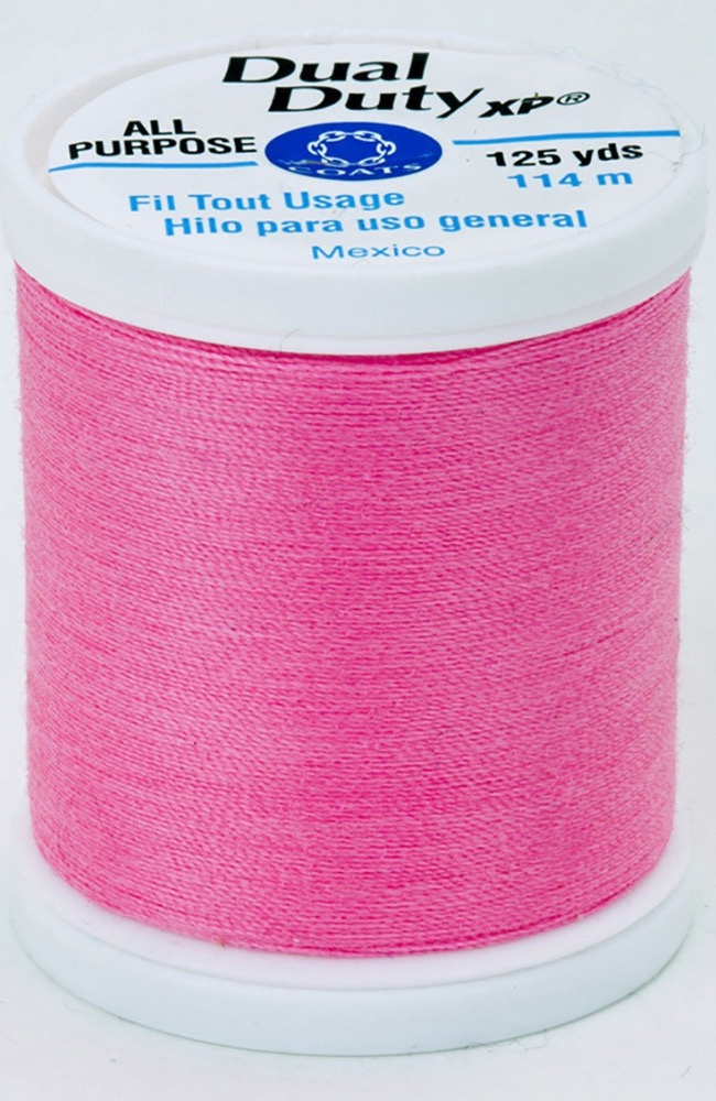 A spool of neon pink Dual Duty XP sewing thread with a white label featuring blue and black text, set against a plain white background.