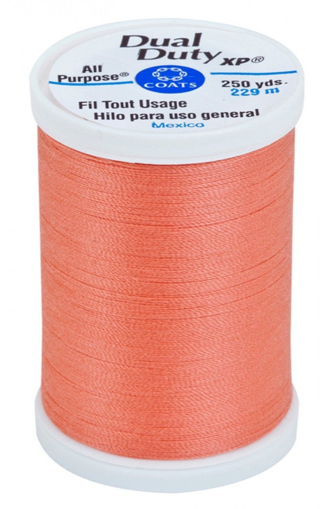 A spool of orange Dual Duty XP sewing thread with a white label featuring blue and black text, set against a plain white background.