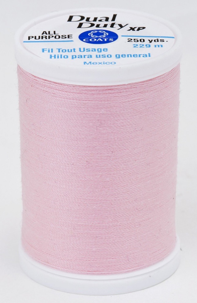 A spool of pink Dual Duty XP sewing thread with a white label featuring blue and black text, set against a plain white background.