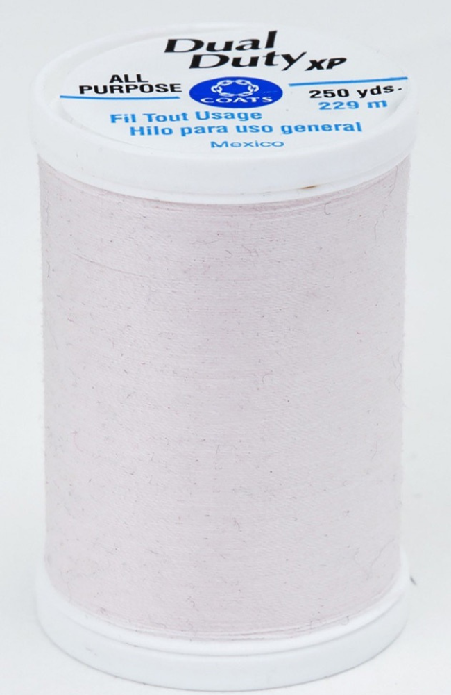 A spool of light pink Dual Duty XP sewing thread with a white label featuring blue and black text, set against a plain white background.