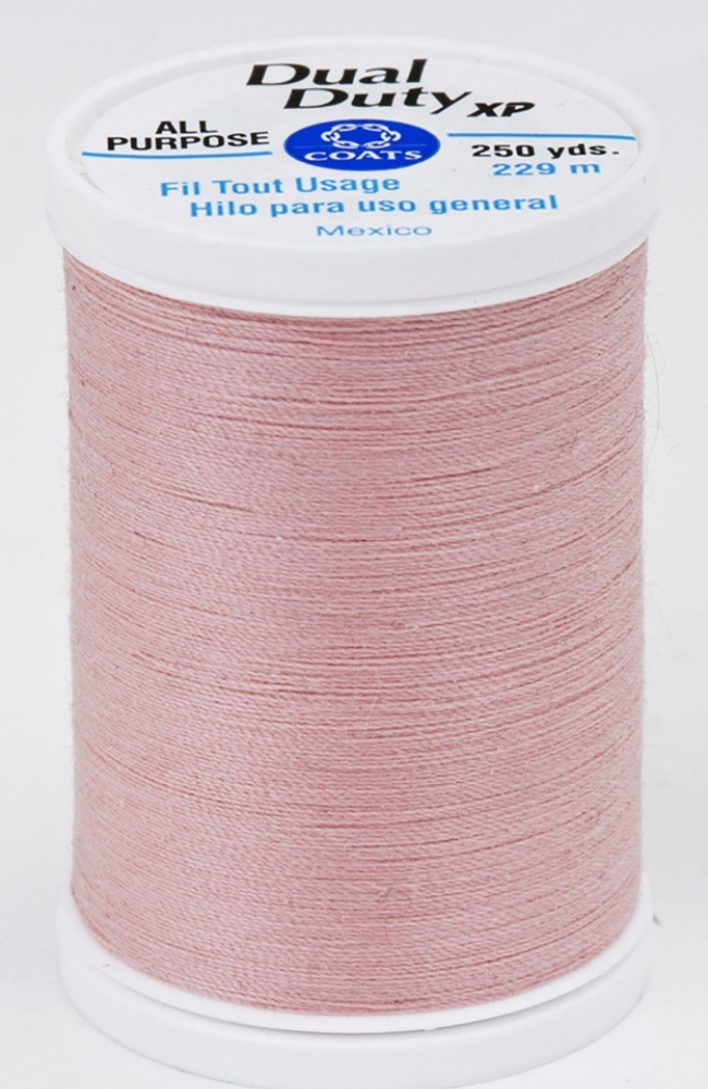 A spool of pink Dual Duty XP sewing thread with a white label featuring blue and black text, set against a plain white background.