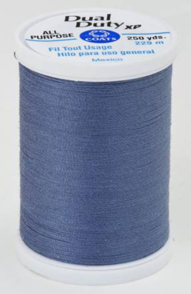 A spool of blue Dual Duty XP sewing thread with a white label featuring blue and black text, set against a plain white background.