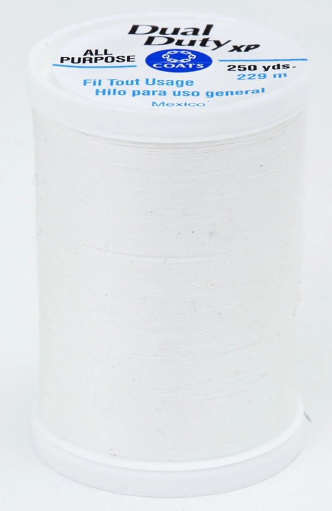 A spool of white Dual Duty XP sewing thread with a white label featuring blue and black text, set against a plain white background.