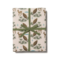 Gift box with images of deer and pine cones and green ribbon on a white background.