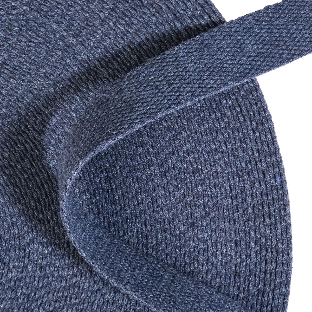 Close up of a roll of blue denim webbing on a white background
