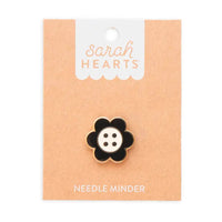 A black and white daisy button needle minder on Sarah Hearts cardboard packaging, on a white background