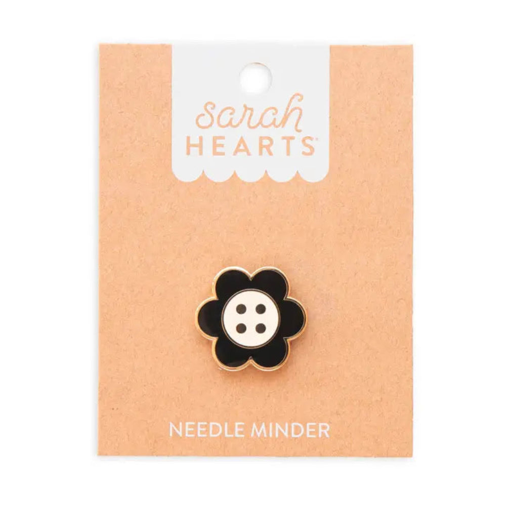 A black and white daisy button needle minder on Sarah Hearts cardboard packaging, on a white background
