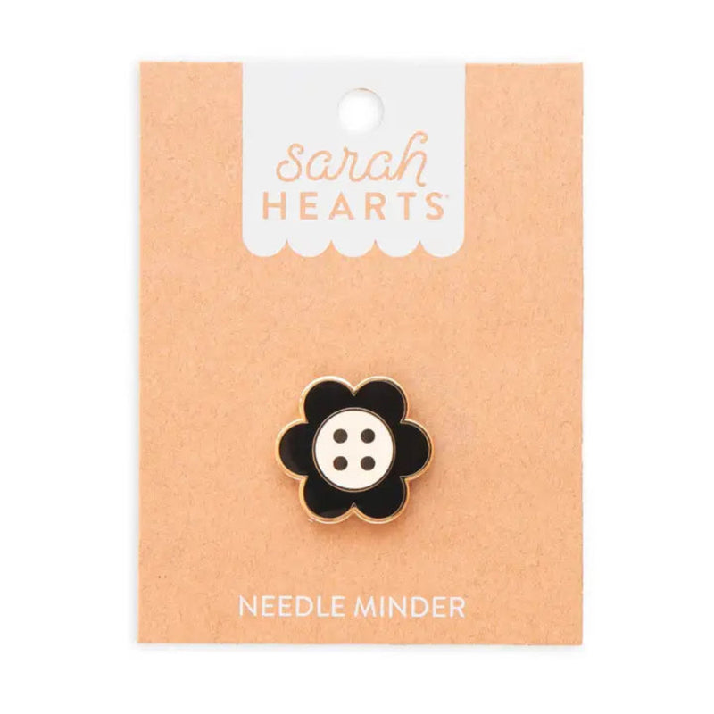 A black and white daisy button needle minder on Sarah Hearts cardboard packaging, on a white background