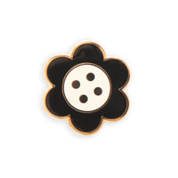 A black and white daisy button needle minder on a white background