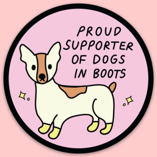 Small dog wearing yellow boots looking forward in pink background and the words "Proud supporter of dogs in boots".