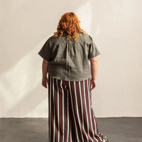 A woman with her back turned wearing a grey shirt.