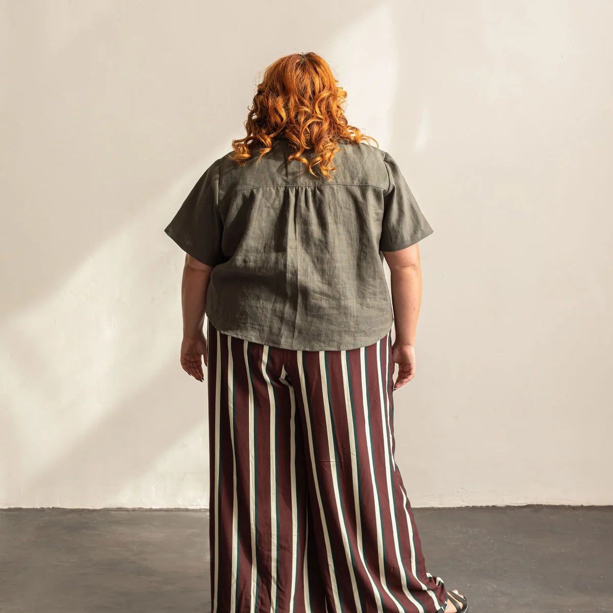 A woman with her back turned wearing a grey shirt.