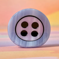 Decorative button with four black holes on a colorful background