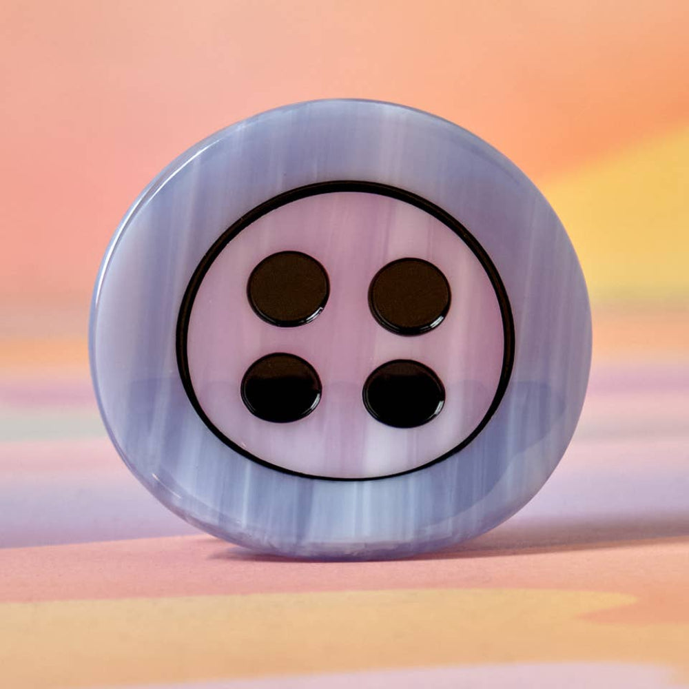 Decorative button with four black holes on a colorful background
